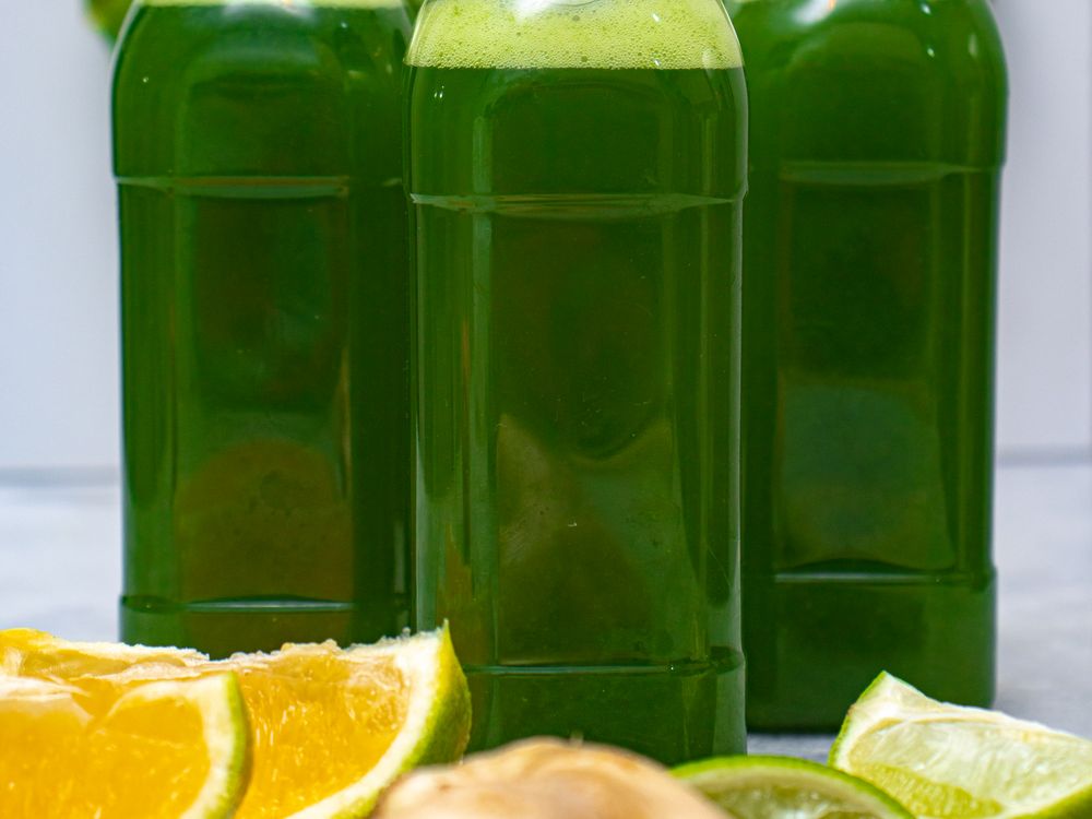 Six chilled bottles of cold-pressed green juice in a row
